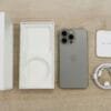 Flat lay view of the newest Apple iPhone model, box, and charging accessories on a wooden table.